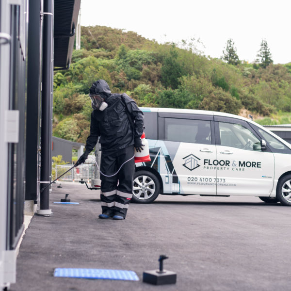 Floor & More - persion performing exterior building cleaning with branded company vehicle in background