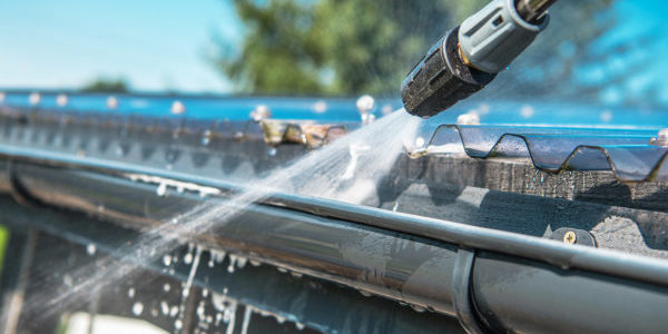 Pressure washing the gutters of a house